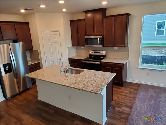 a kitchen with stainless steel appliances wooden floors and wooden cabinets