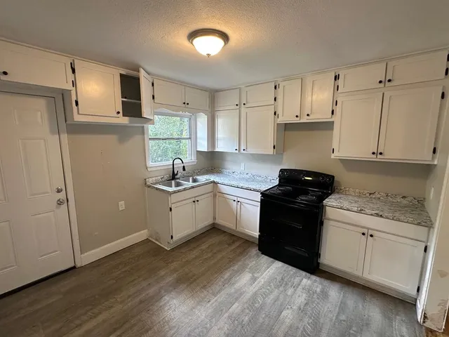 a kitchen with granite countertop white cabinets and white appliances