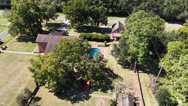 an aerial view of residential house with outdoor space and trees all around