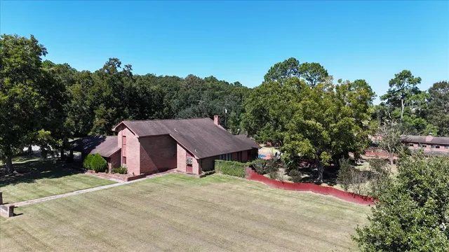 an aerial view of a house with yard and trees in the background