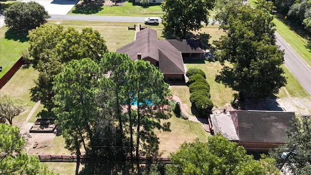 an aerial view of residential house with outdoor space and trees all around
