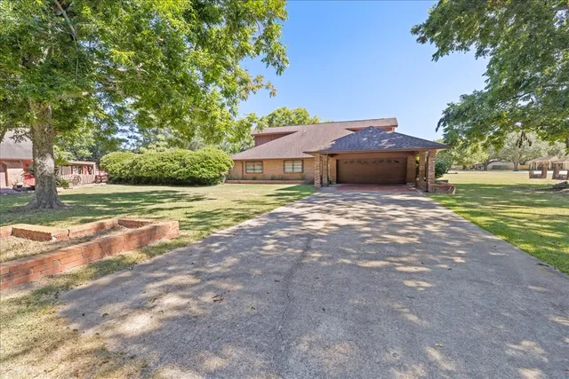 a view of a house with a yard and large tree