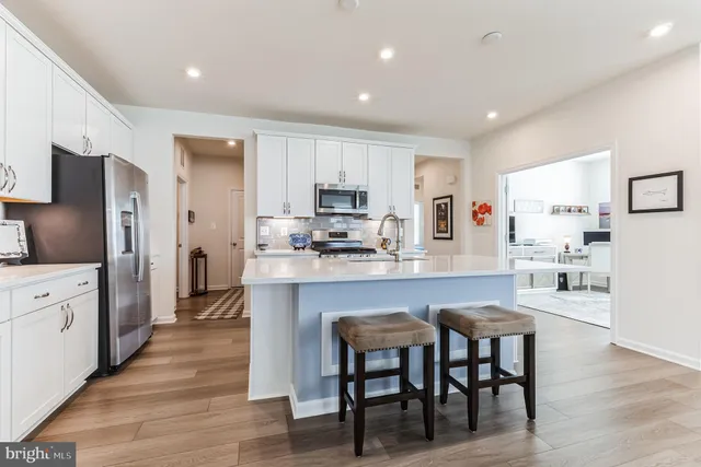 a kitchen with stainless steel appliances granite countertop a refrigerator a stove top oven a sink dishwasher and white cabinets with wooden floor