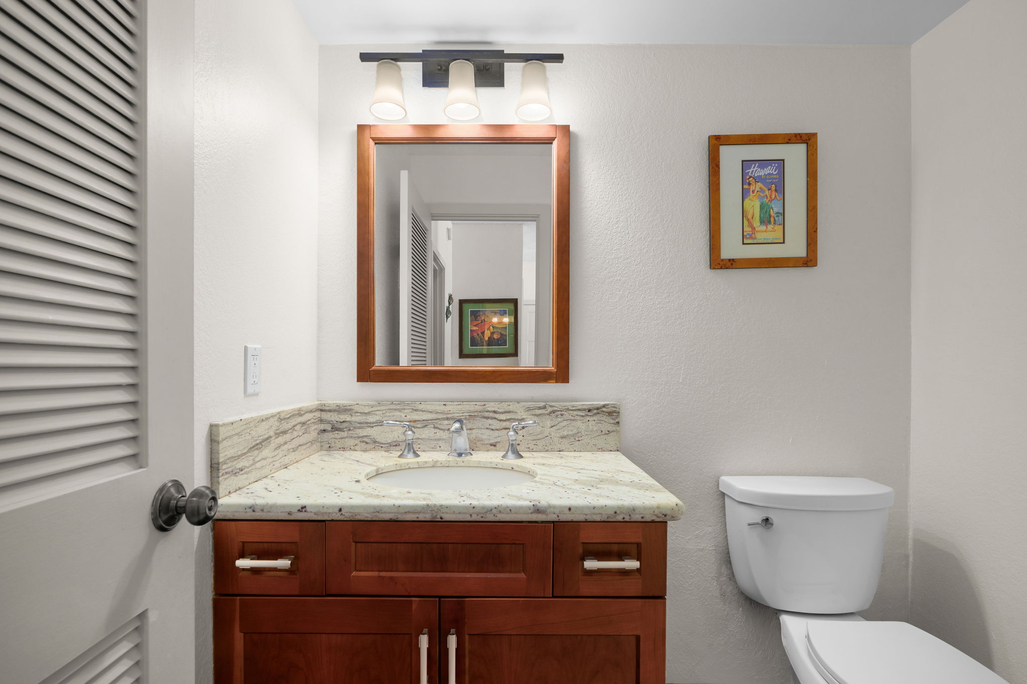 1565 Pe'e Road, Unit 418 Koloa, HI 96756 - Photo 16 of 30 a bathroom with a granite countertop toilet a sink and mirror