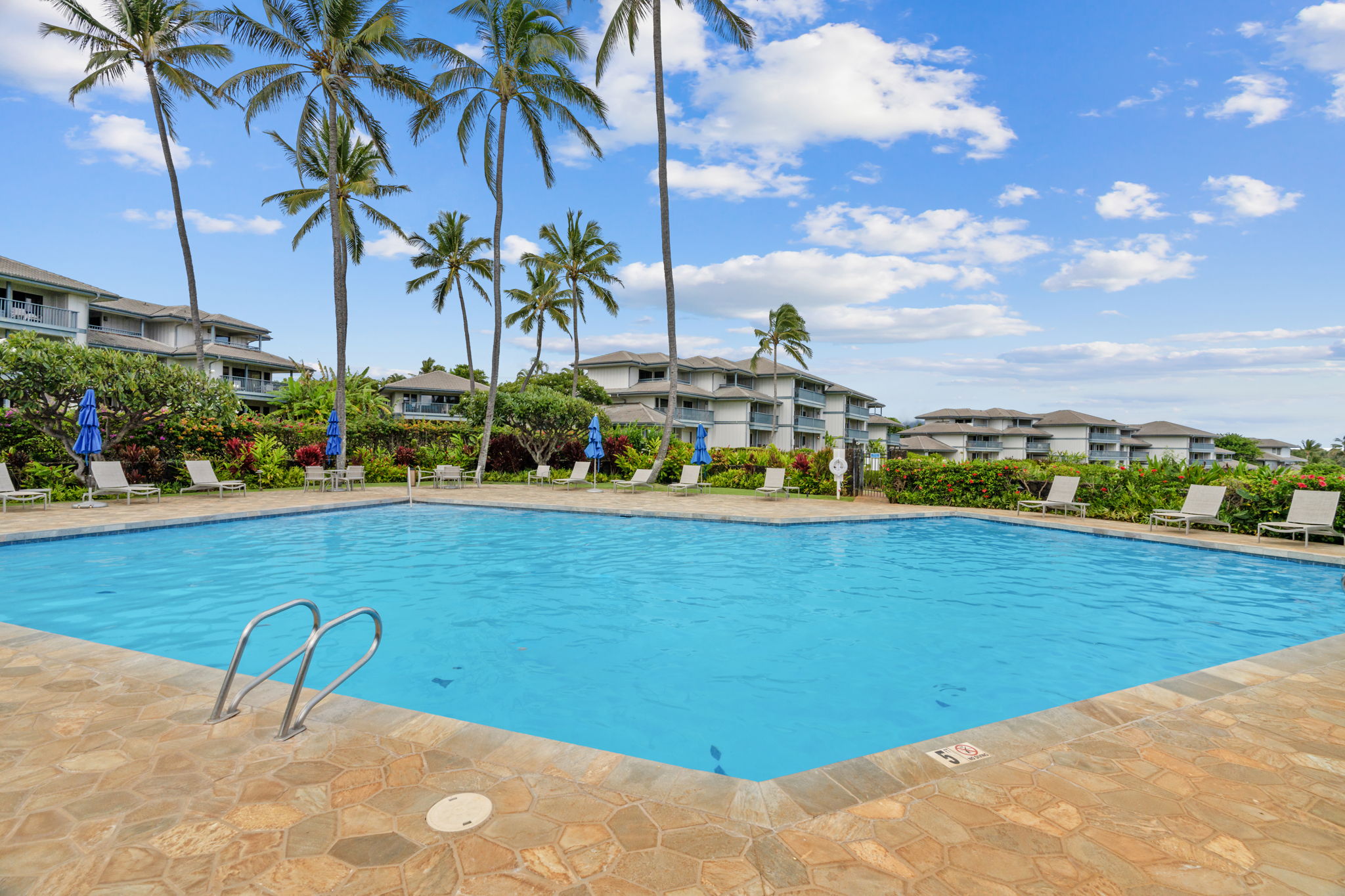 1565 Pe'e Road, Unit 418 Koloa, HI 96756 - Photo 21 of 30 a view of a swimming pool with a lawn chairs under an umbrella