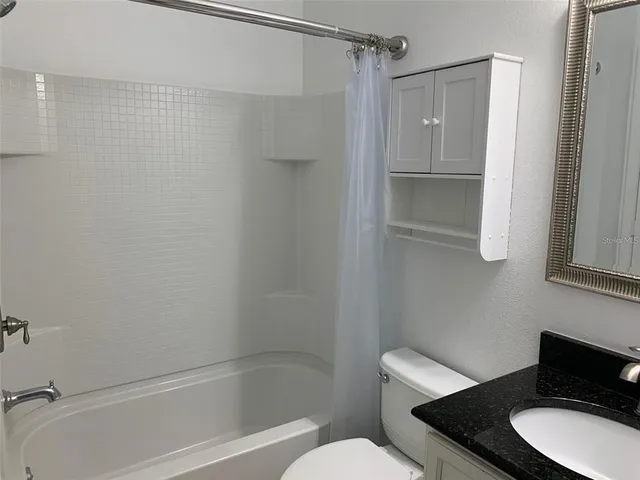 a bathroom with a granite countertop toilet sink and shower