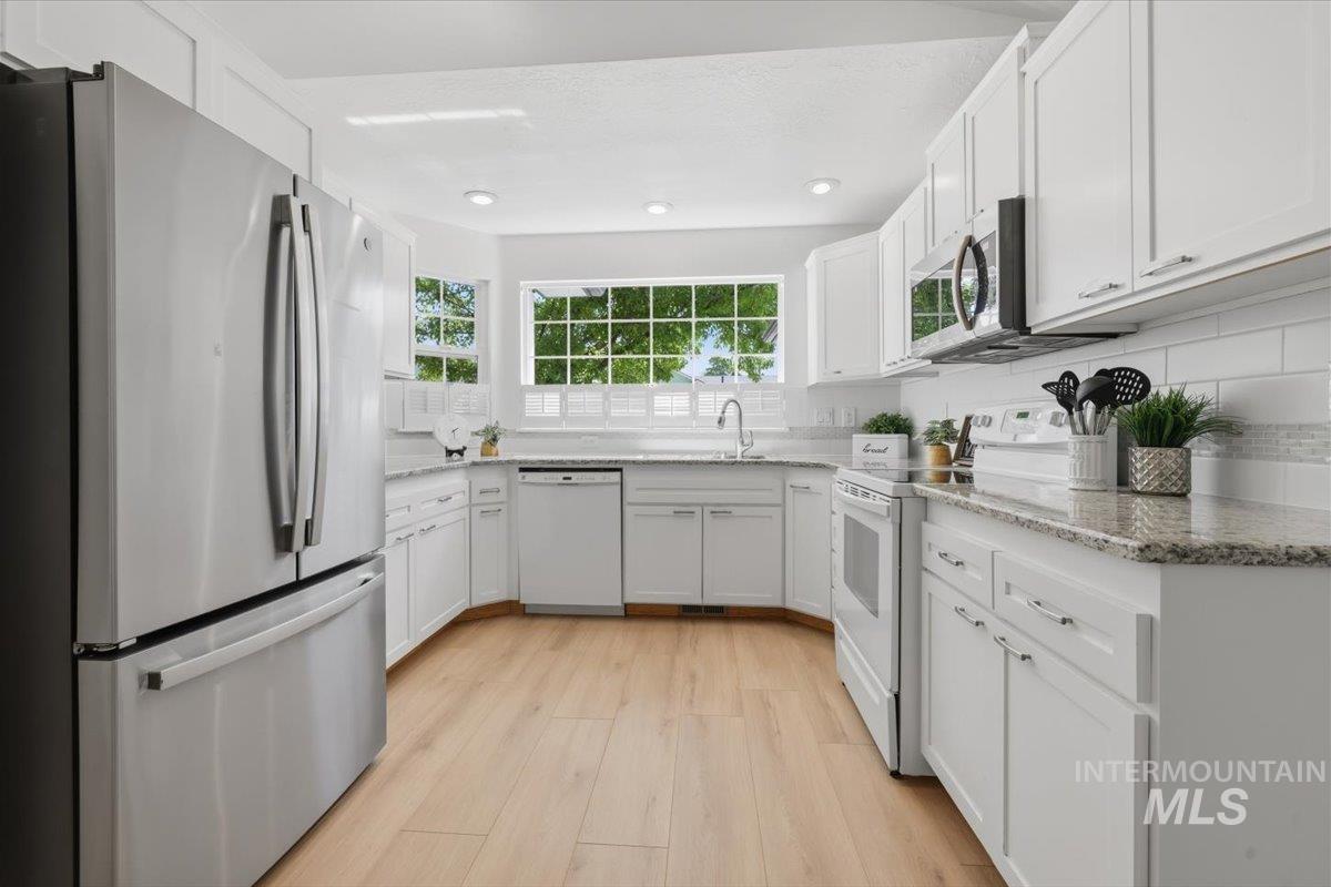 2075 North Springland Place Boise, ID 83713 - Photo 11 of 49 Contemporary kitchen featuring white cabinetry, light granite countertops, stainless steel appliances, and wood-finish flooring