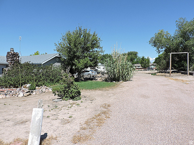 355 South Center Street Delta, UT 84624 - Photo 21 of 21 Gravel driveway extending towards a single-story residence with a grey roof and siding