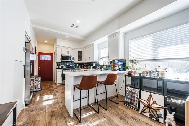 a kitchen with stainless steel appliances granite countertop a stove top oven a sink dishwasher and white cabinets with wooden floor