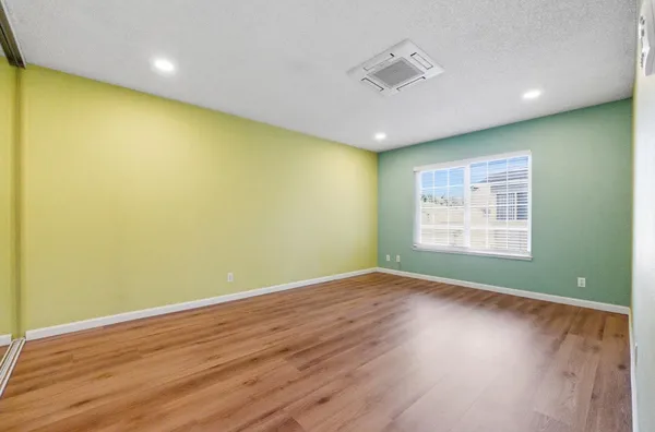 an empty room with wooden floor and windows