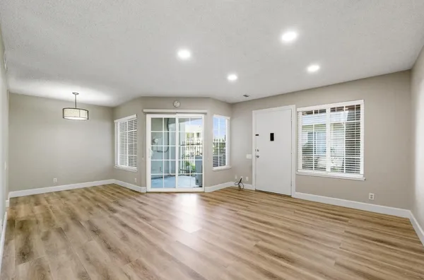 a view of an empty room with wooden floor and a window