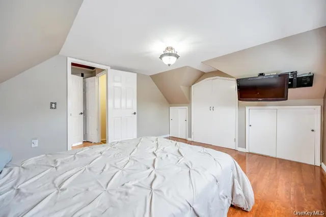 a bedroom with a bed and a flat tv screen on dresser