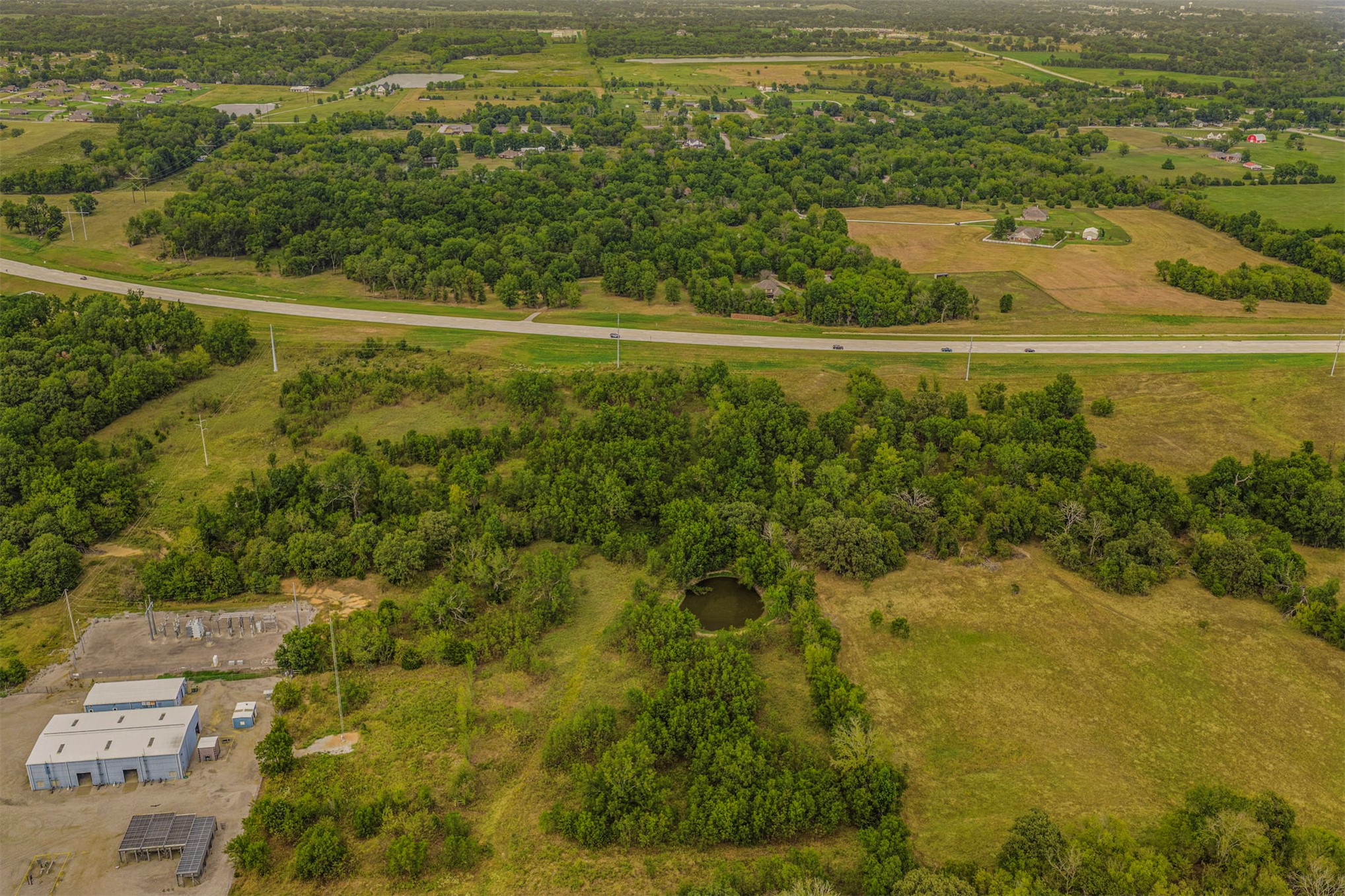 King Road Claremore, OK 74019 - Photo 24 of 45 Expansive acreage featuring a natural pond, surrounding mature trees, open grassy areas, and commercial-style structures