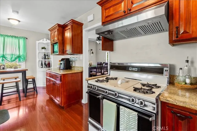 a kitchen with stainless steel appliances granite countertop a stove a sink and a wooden cabinets