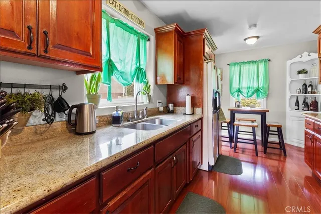 a kitchen with stainless steel appliances granite countertop a stove a refrigerator a sink dishwasher with a dining table and chairs with wooden floor