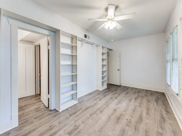 an empty room with a windows and a ceiling fan