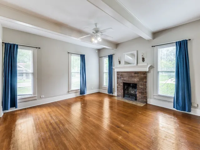 a view of an empty room with wooden floor fireplace and a window