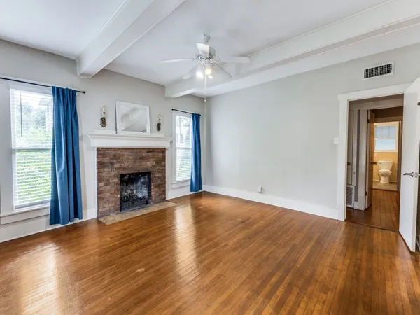 a view of an empty room with wooden floor fireplace and a window