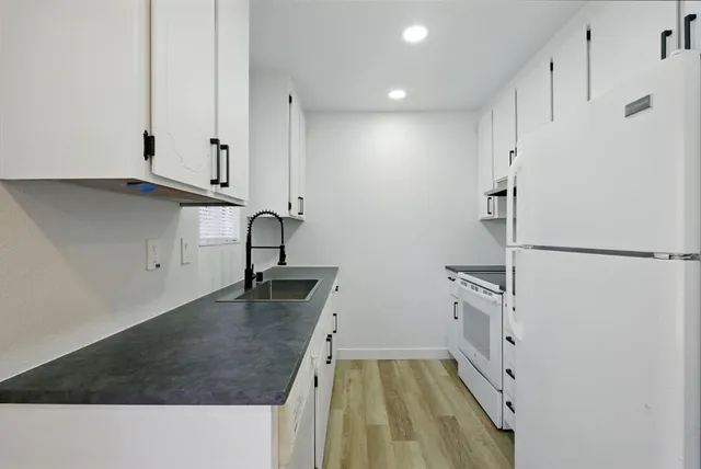 a kitchen with granite countertop white cabinets and white appliances