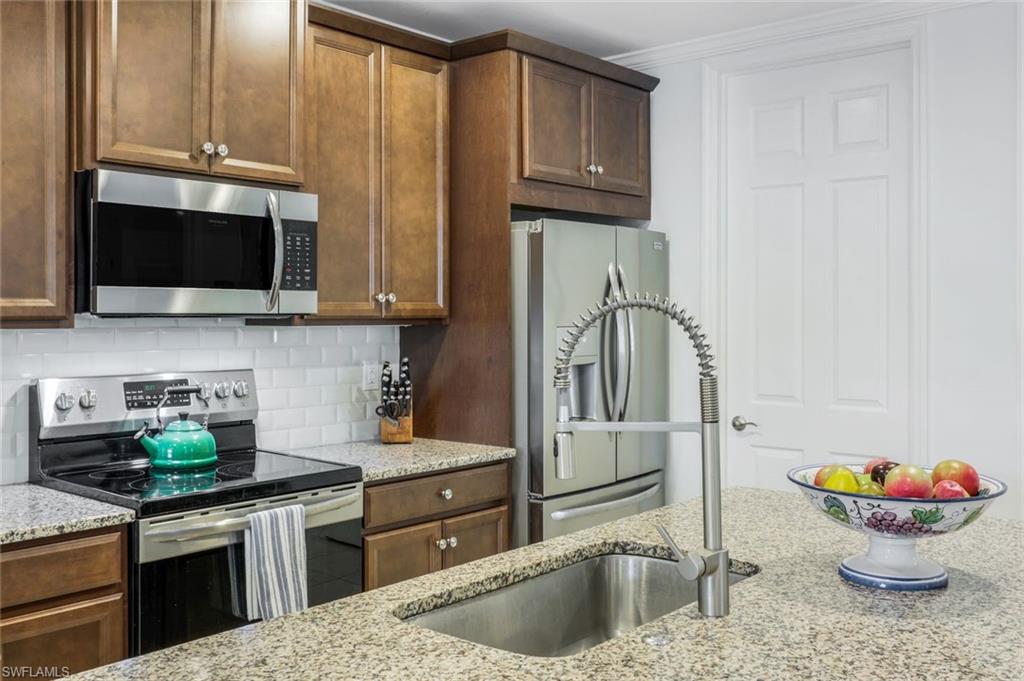 14795 Edgewater Circle Naples, FL 34114 - Photo 7 of 39 a kitchen with stainless steel appliances granite countertop a sink stove and refrigerator