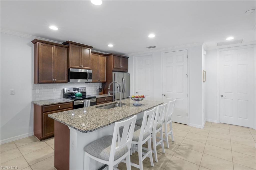 14795 Edgewater Circle Naples, FL 34114 - Photo 8 of 39 a kitchen with stainless steel appliances granite countertop a sink a stove a microwave a counter top space and cabinets