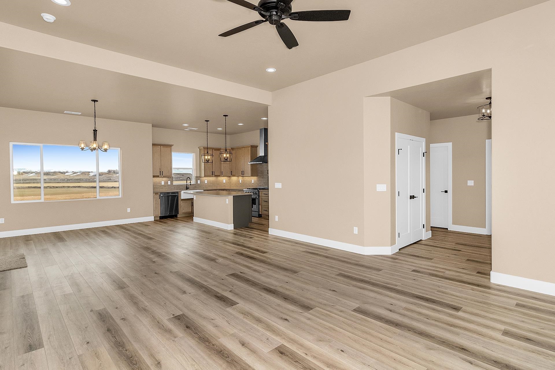 1656 8 Road Mack, CO 81525 - Photo 8 of 28 an empty room with wooden floor kitchen view and a chandelier fan