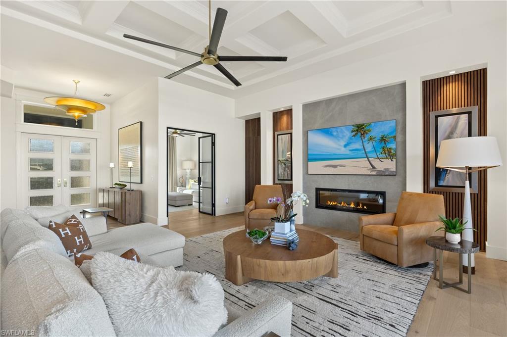 1955 Tarpon Road Naples, FL 34102 - Photo 5 of 48 Living area with wood finished floors, a large fireplace, coffered ceiling, beamed ceiling, and french doors