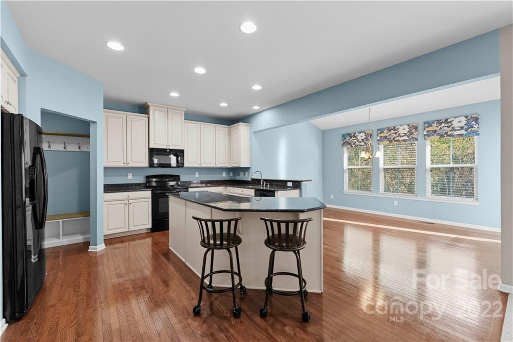 7720 East Berkeley Road Denver, NC 28037 - Photo 8 of 40 a kitchen with stainless steel appliances granite countertop a stove a refrigerator a sink a dining table and chairs with wooden floor