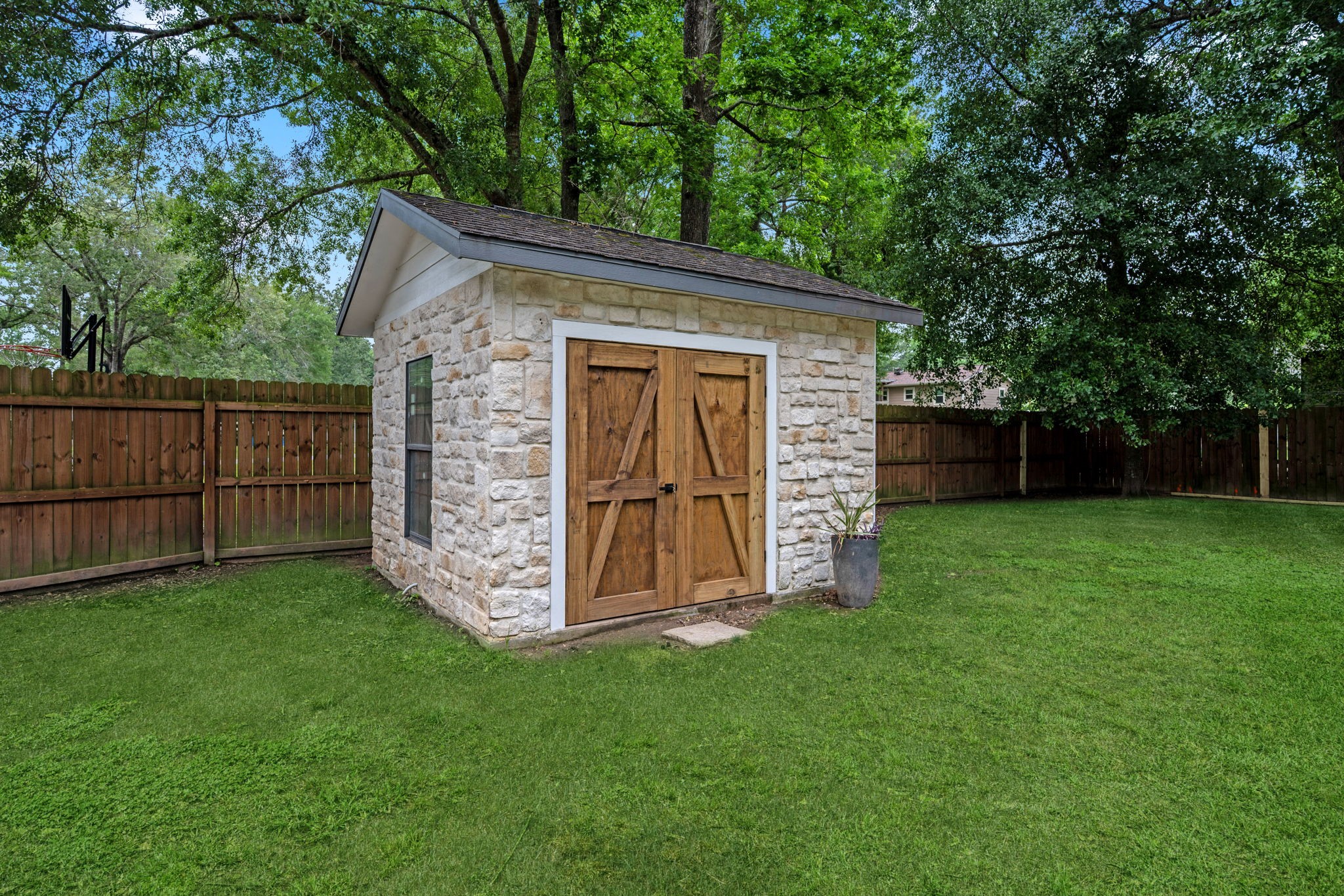 18 East Old Field Road Huffman, TX 77336 - Photo 29 of 35 Pump house building beautifully finished with stone-inspired exterior detailing and rustic barn-style doors, offering both functionality & aesthetic appeal which houses the well head, pool pump and pool equipment as well as ample storage.