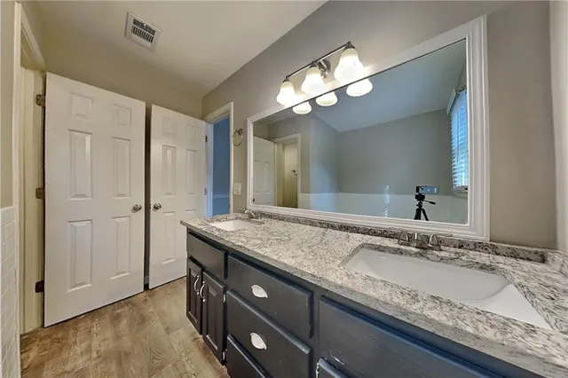 a bathroom with a granite countertop double vanity sink and a mirror
