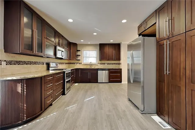a large kitchen with stainless steel appliances granite countertop wooden cabinets a sink and a stove