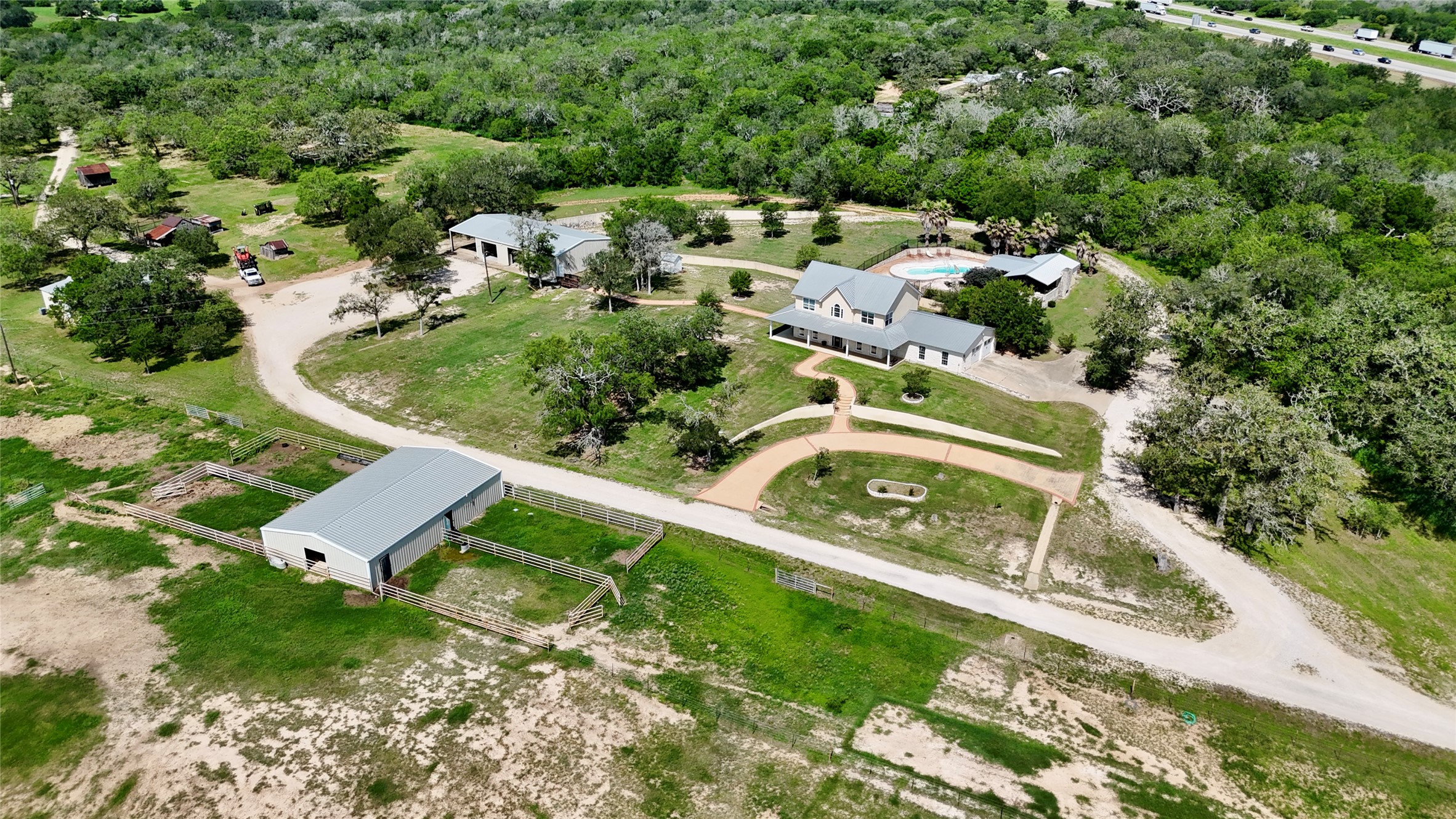 An aerial panorama reveals a private oasis, blending modern living with rustic charm on expansive grounds.