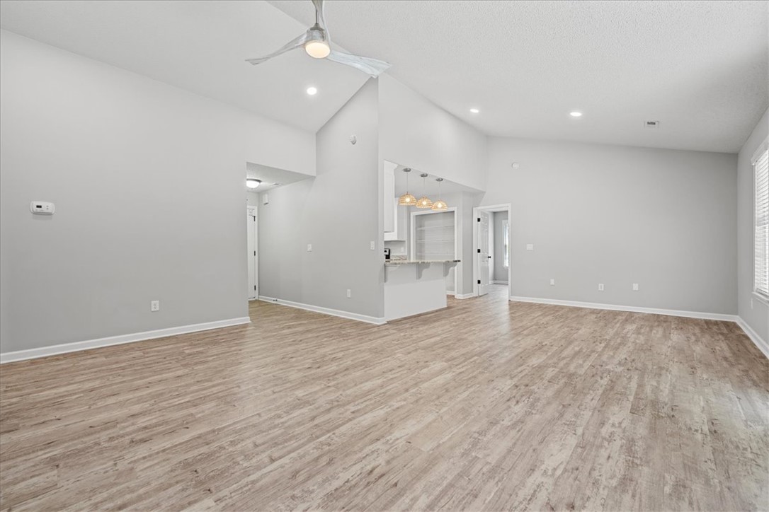 212 Blue Ridge Drive Clemson, SC 29631 - Photo 32 of 33 An open floorplan with vaulted ceilings and light wood-look flooring connects living and kitchen spaces.