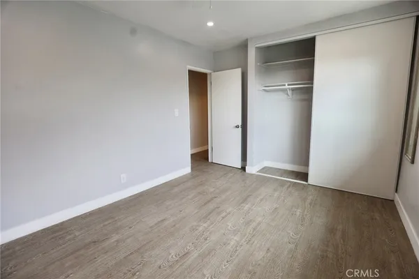 a view of an empty room with wooden floor and closet
