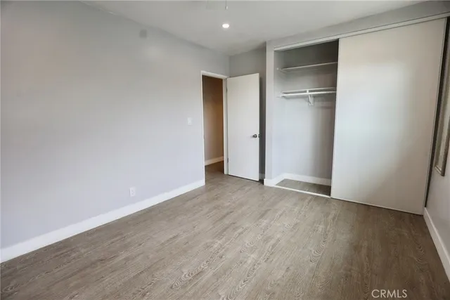 a view of an empty room with wooden floor and closet