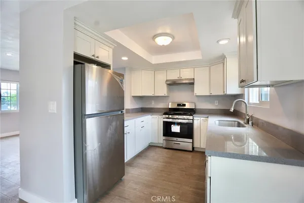a kitchen with a refrigerator a stove a sink and white cabinets