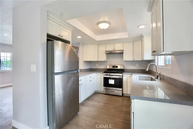 a kitchen with a refrigerator a stove a sink and white cabinets