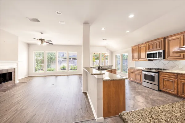 a open kitchen with stainless steel appliances granite countertop a stove top oven a sink dishwasher and a fireplace with wooden floor