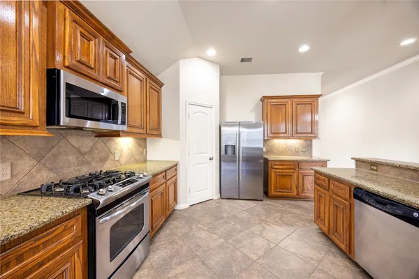 a kitchen with stainless steel appliances granite countertop a stove top oven a refrigerator a sink and dishwasher with wooden floor