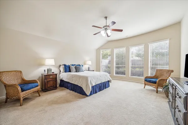 a spacious bedroom with a bed and glass chair