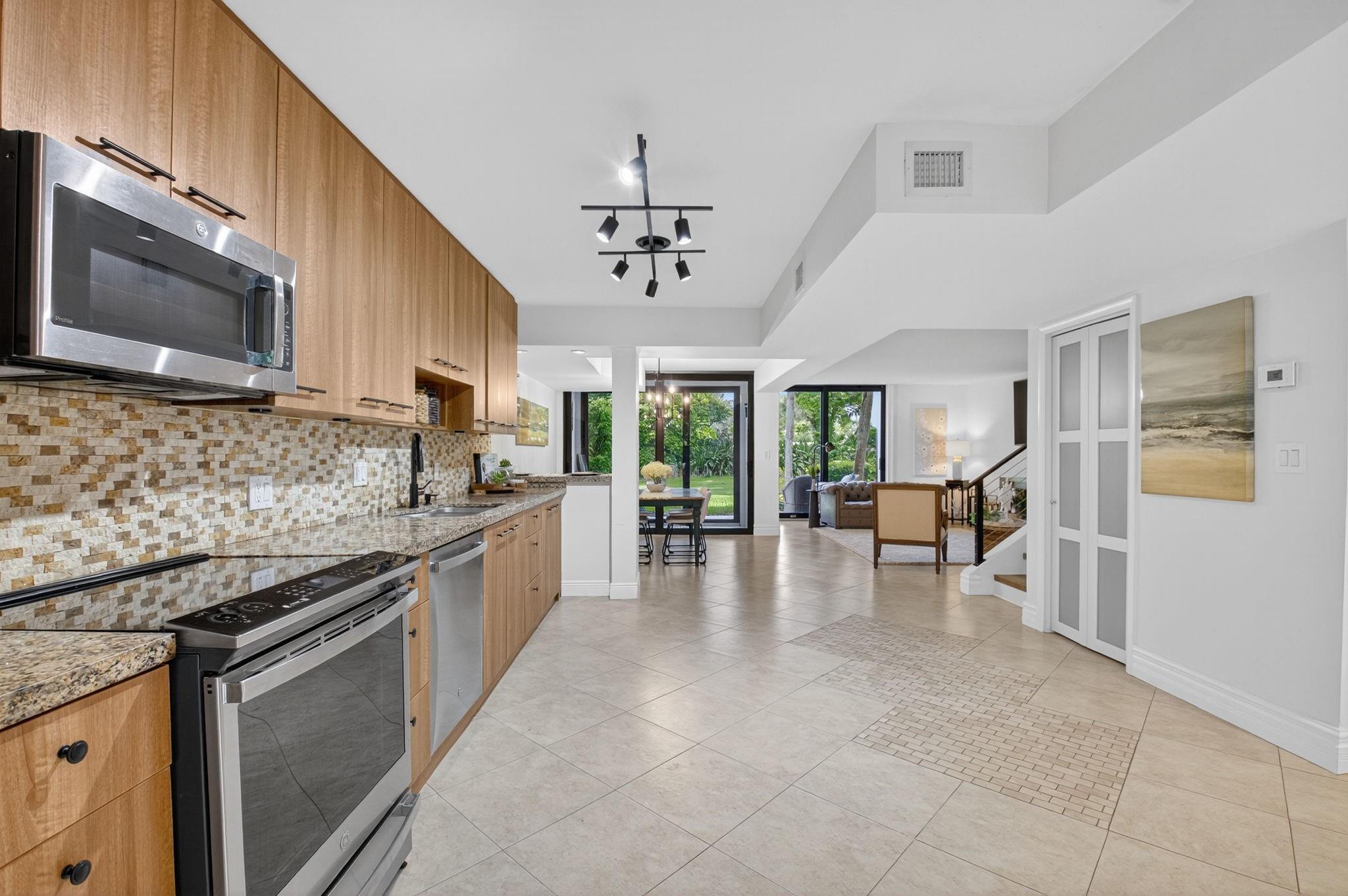 3802 Bridgewood Drive Boca Raton, FL 33434 - Photo 30 of 46 a large kitchen with stainless steel appliances granite countertop a stove top oven a sink dishwasher a dining table and chairs with wooden floor