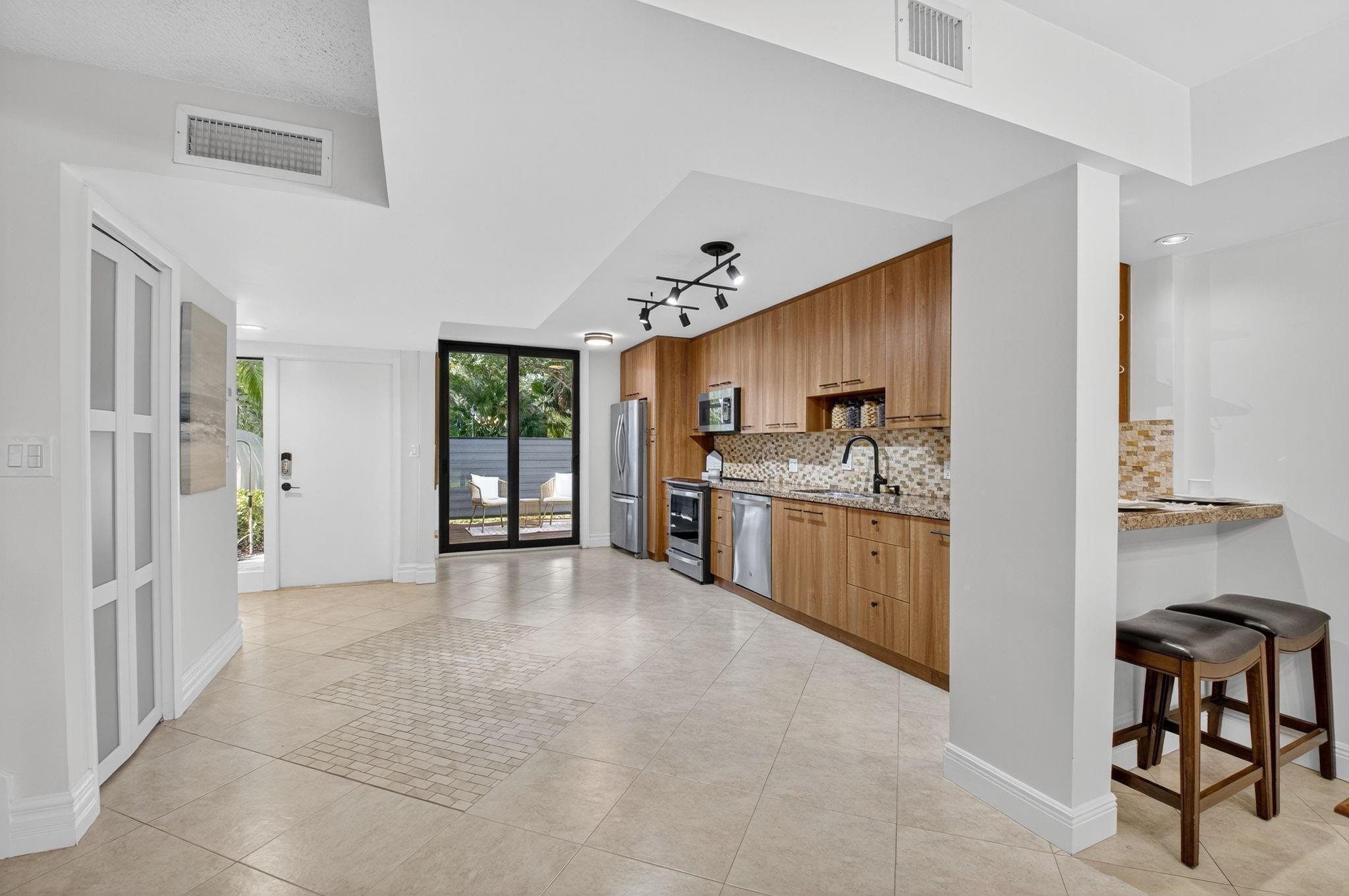 3802 Bridgewood Drive Boca Raton, FL 33434 - Photo 5 of 46 a large white kitchen with cabinets a sink a window and stainless steel appliances