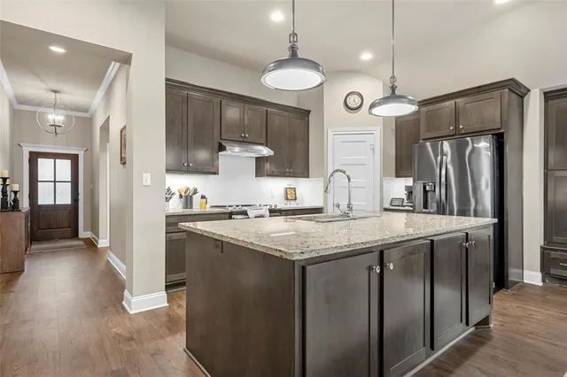 a kitchen with stainless steel appliances granite countertop a sink a refrigerator and a stove top oven