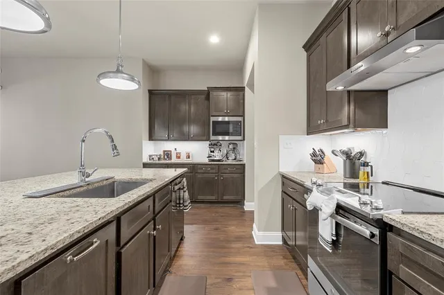 a kitchen with stainless steel appliances granite countertop a sink stove and refrigerator