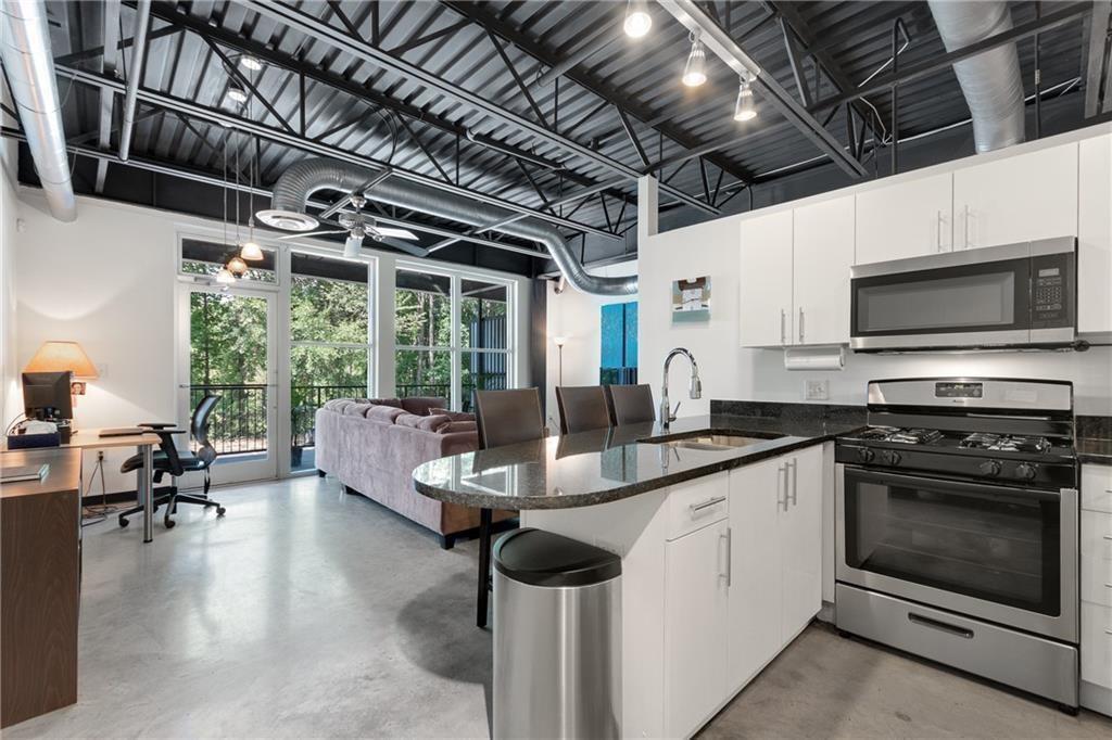 5200 Peachtree Road, Unit 3120 Atlanta, GA 30341 - Photo 1 of 1 a kitchen with stainless steel appliances granite countertop a stove and a view of living room