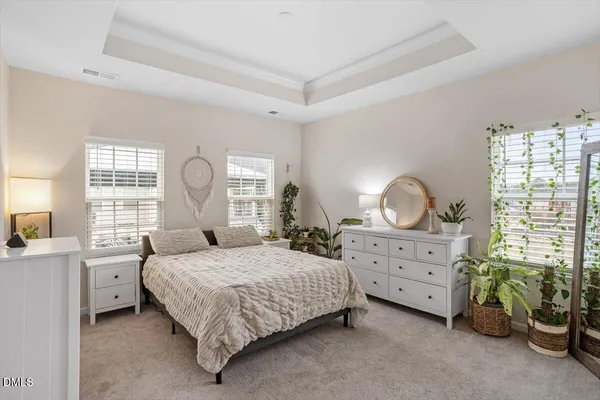 a bedroom with a bed a chandelier and dresser