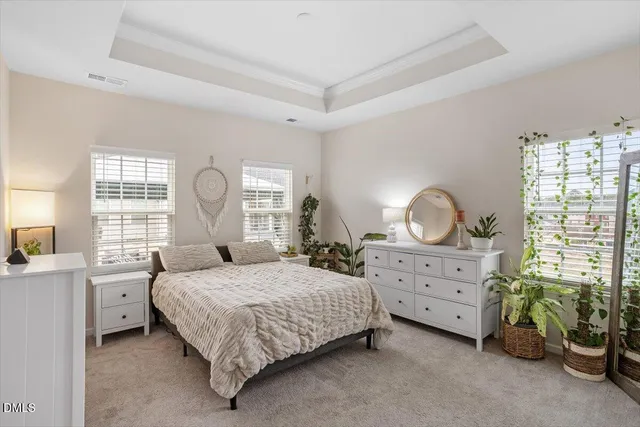 a bedroom with a bed a chandelier and dresser