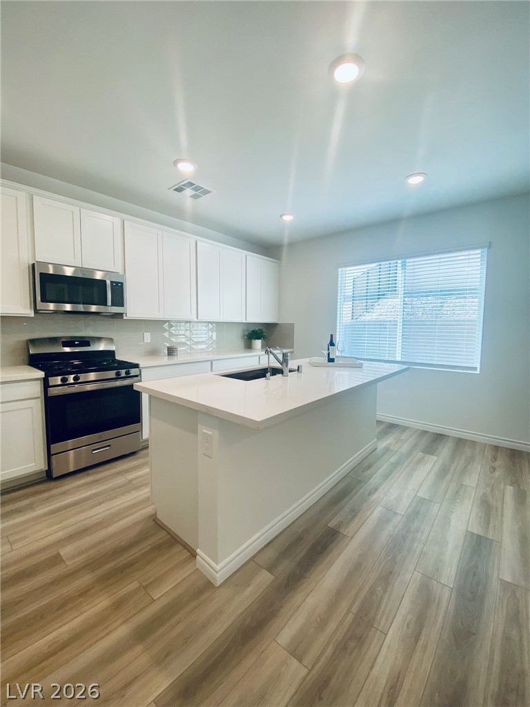 4457 Sawyer Ridge Street Las Vegas, NV 89147 - Photo 13 of 32 This modern kitchen features light-toned flooring, white cabinetry, and stainless steel appliances.