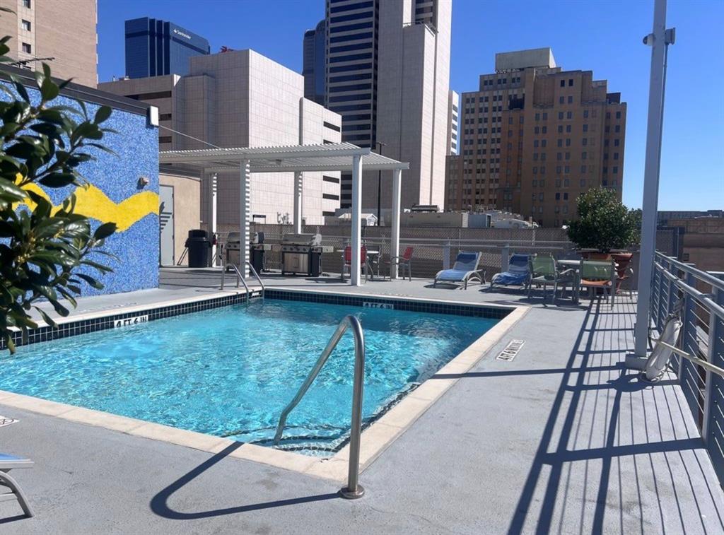 1122 Jackson Street, Unit 514 Dallas, TX 75202 - Photo 34 of 40 Rooftop pool deck featuring a mosaic-tiled wall, stainless steel pool handrails, and a shaded outdoor kitchen area with multiple grills