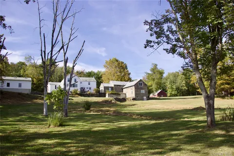 a view of a house with a big yard and large trees